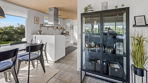 A modern kitchen with white cabinets, a glass-fronted display case, and a dining area with a table and chairs.