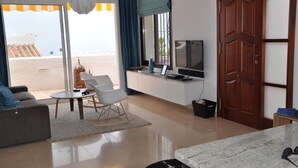 Un soggiorno moderno con un divano, un tavolino, una televisione e un'area pranzo con tavolo e sedie.