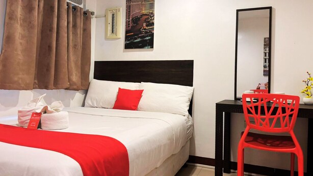 Une chambre d’hôtel équipée d’un lit, d’un bureau, d’une chaise, d’un miroir et d’un climatiseur fixé au mur.