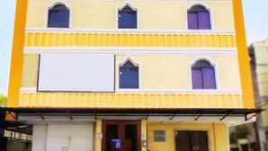 Un immeuble à plusieurs étages, doté d’une façade jaune et de bordures blanches.