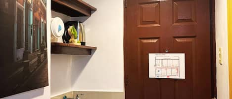 Una cocina compacta con un lavabo, una puerta de madera y un estante con una planta.