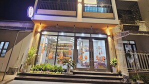 A multi-story building with a brightly lit storefront and a neon sign reading "ZingHome". - ZingHome Ha Giang (Ha Giang 1)