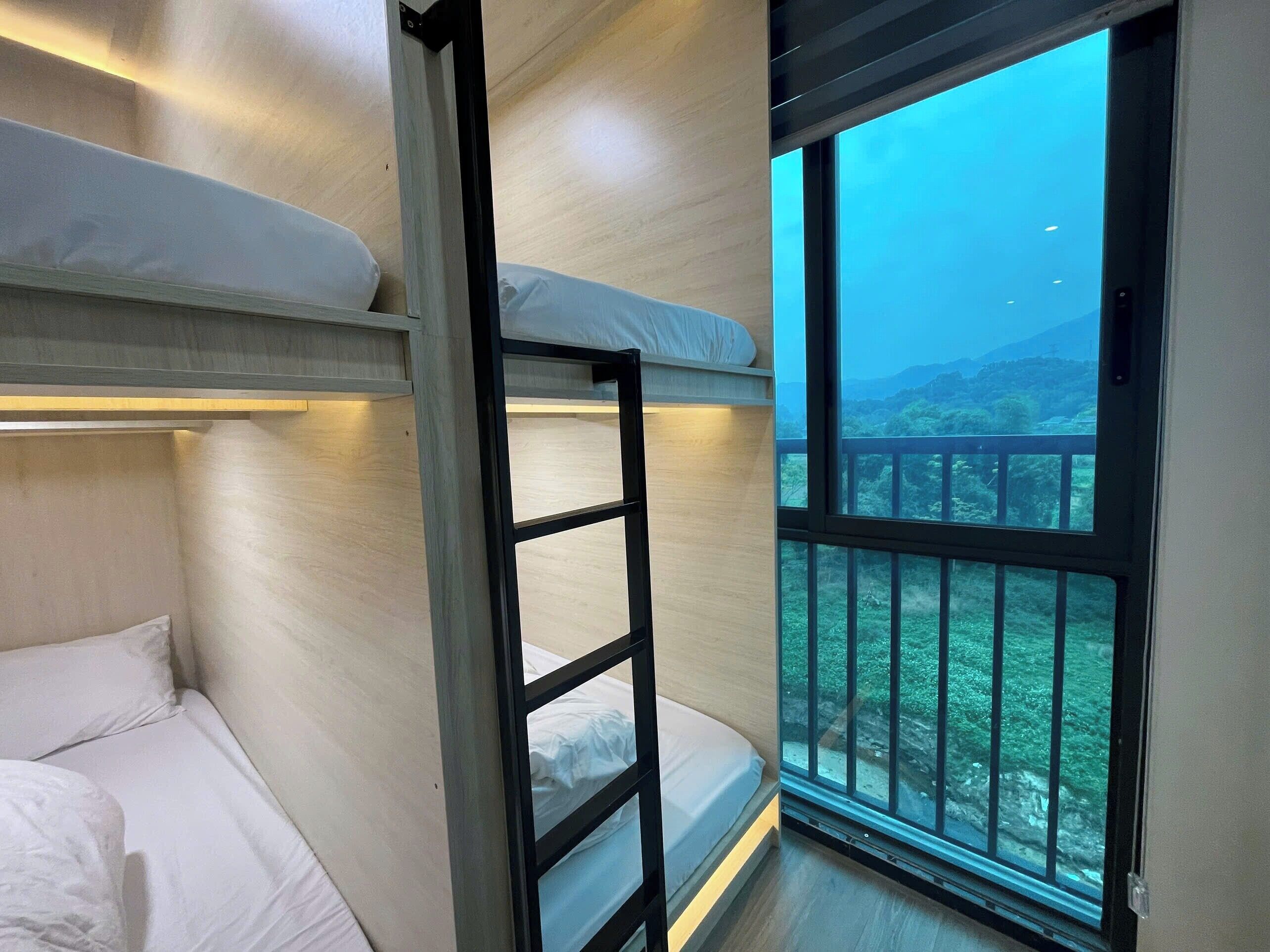 A bunk bed room with a view of a mountainous landscape through a large window.