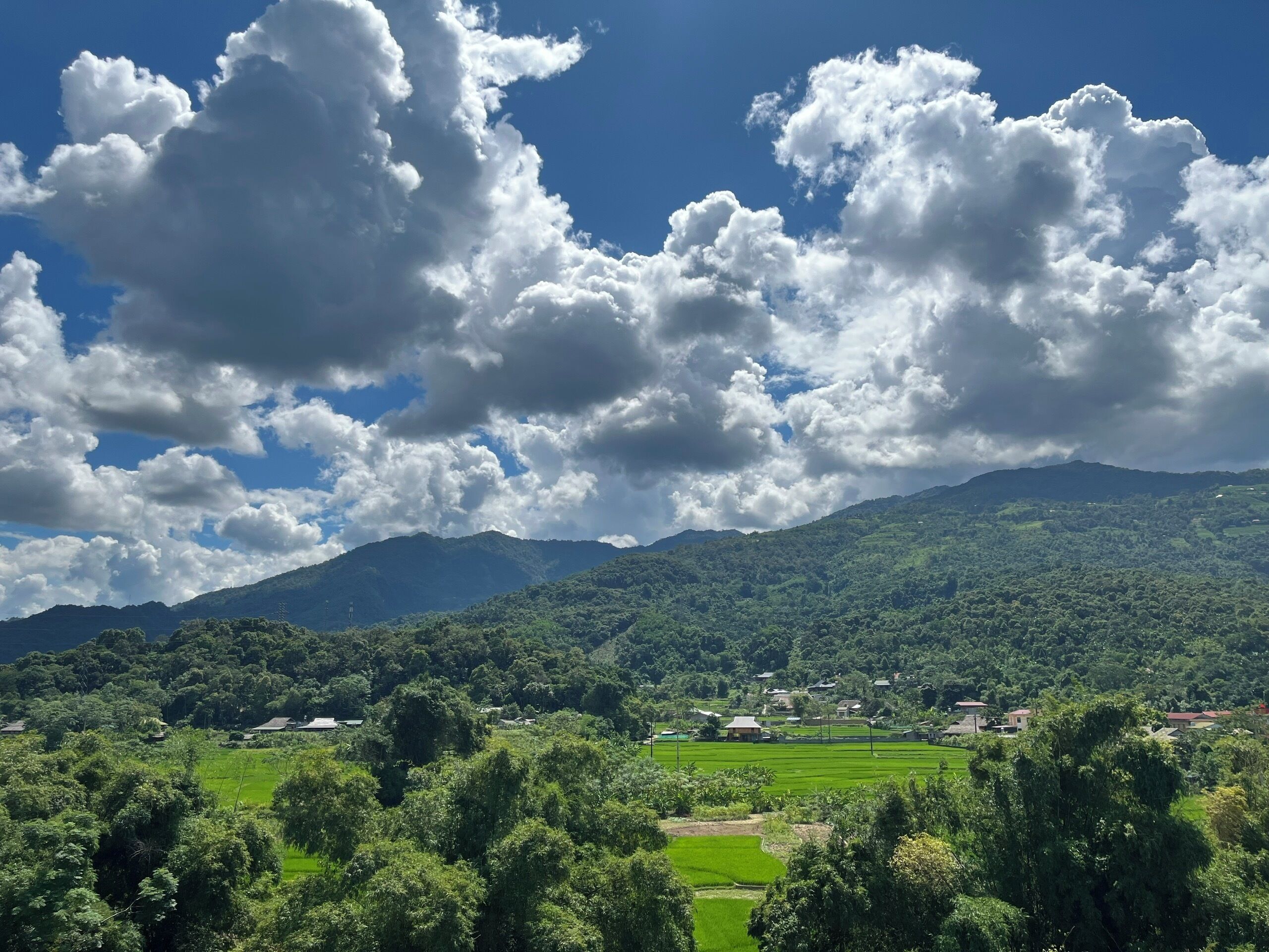 A landscape with a mountain range, green fields, and scattered houses.