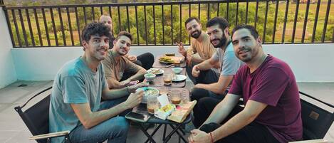 Un grupo de personas sentadas a una mesa con vistas a montañas y follaje.