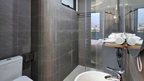 A modern bathroom with a toilet, a large sink, and a glass-enclosed shower area. - ZingHome Ha Giang (Ha Giang 1)