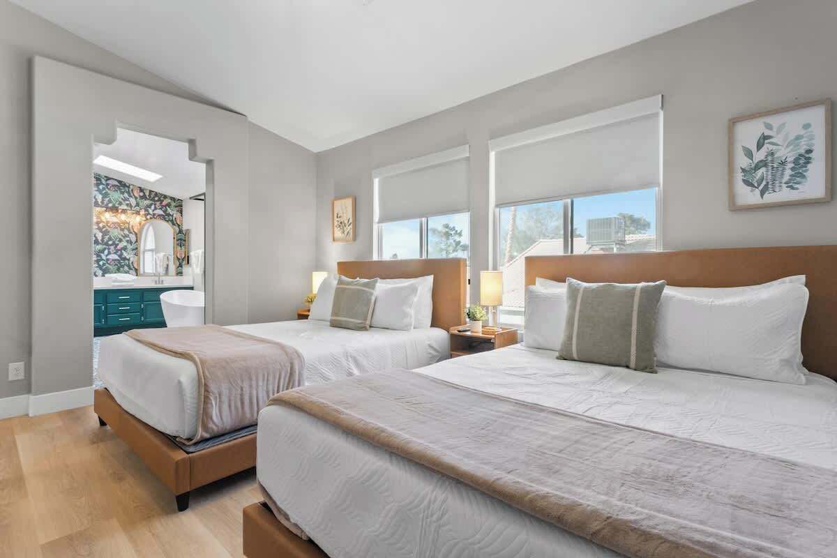 Een hotelkamer met twee bedden, een groot raam en uitzicht op buiten.