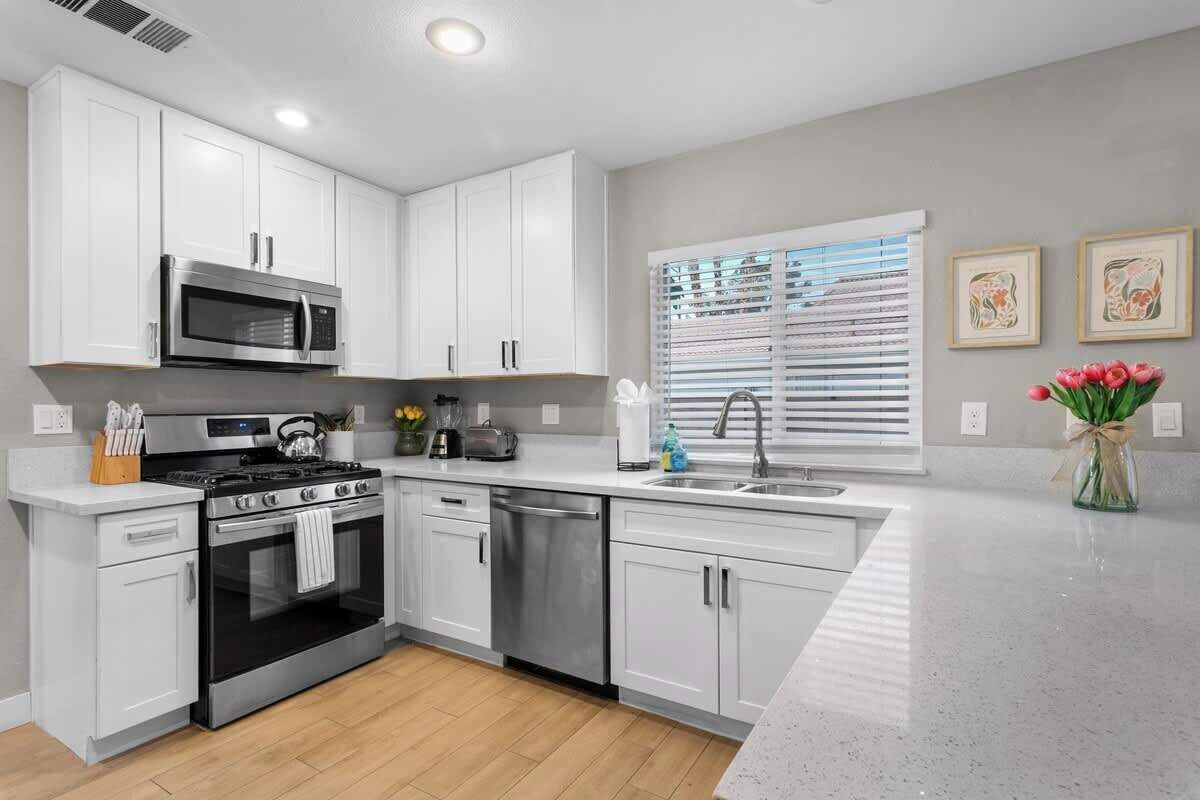 Una cocina moderna con armarios blancos, electrodomésticos de acero inoxidable y encimera de madera.