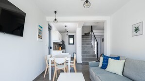 A modern living room with a grey sofa, a white coffee table, and a dining area with a white table and chairs. - Villa Artec with Sea View and Private Pool (Marcana)