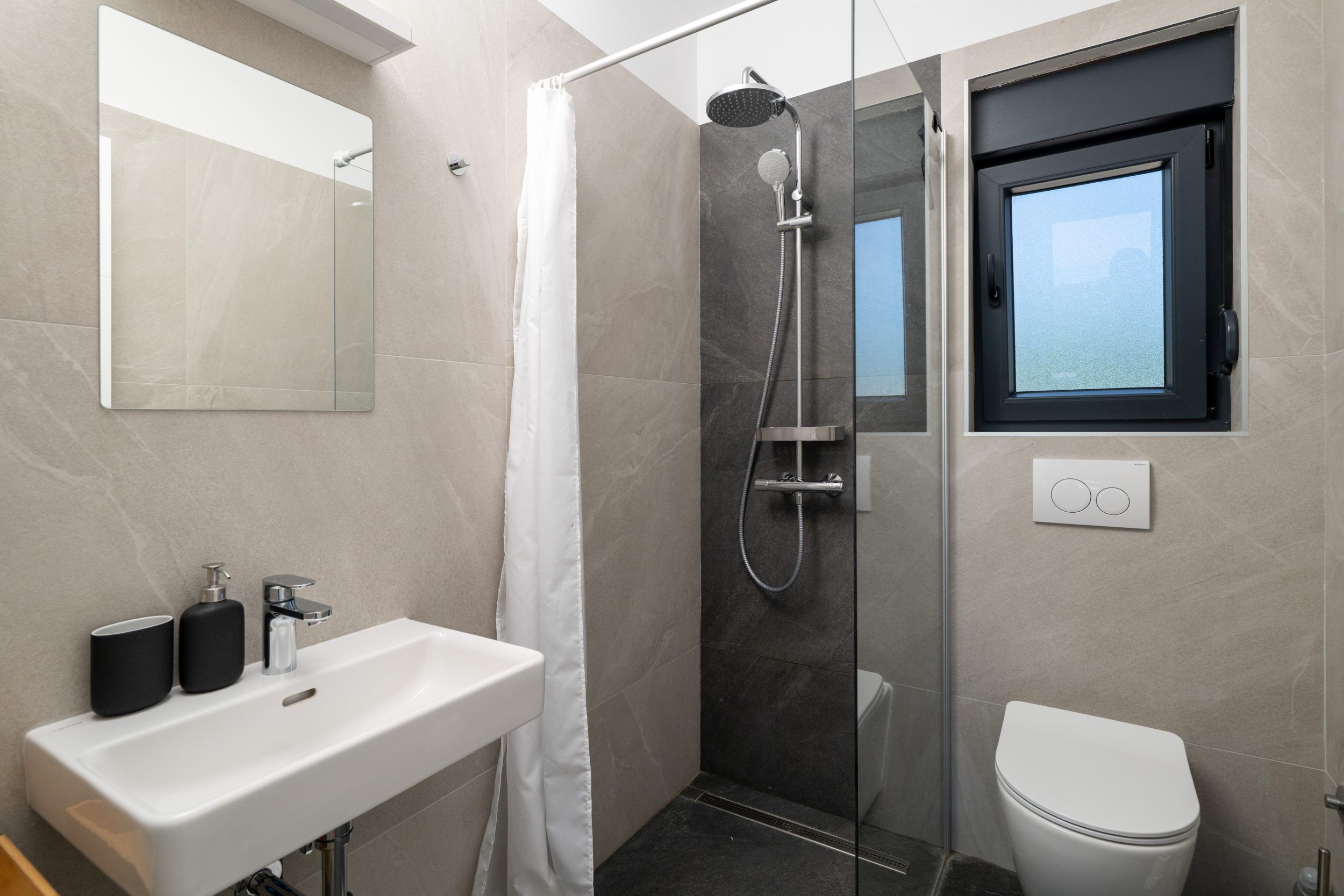 A modern bathroom with a shower, toilet, and sink.