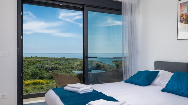 A bedroom with a bed, pillows, and a view of the sea. - Villa Artec with Sea View and Private Pool (Marcana)