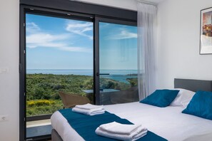 Ein Schlafzimmer mit Bett, Kissen und Meerblick.