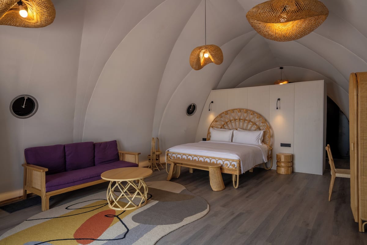 A cozy bedroom with a bed, a purple sofa, and a small round table.