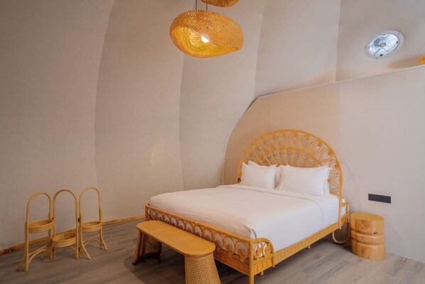 A room with a bed, wicker furniture, and a bench.