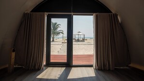 Una habitación con un gran ventanal corredizo que da a la playa.