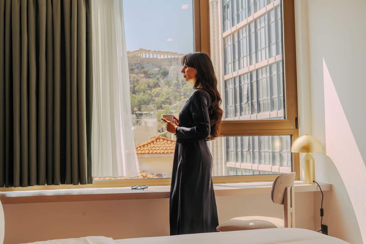 A room with a large window, a bed, a chair, and a lamp.
