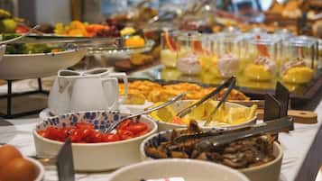 Un bufé con diversas opciones de comida, incluyendo frutas, verduras y platos preparados.