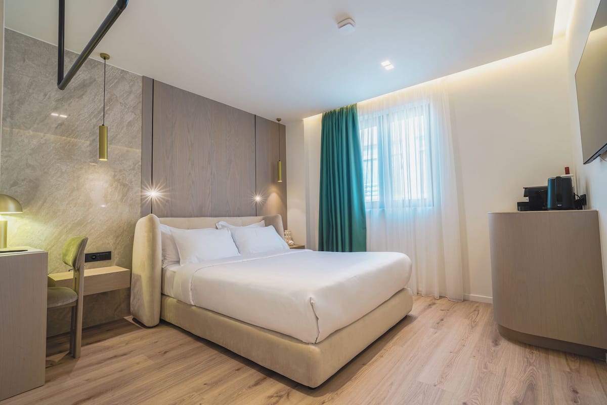 A modern bedroom with a large bed, a desk, and a TV.
