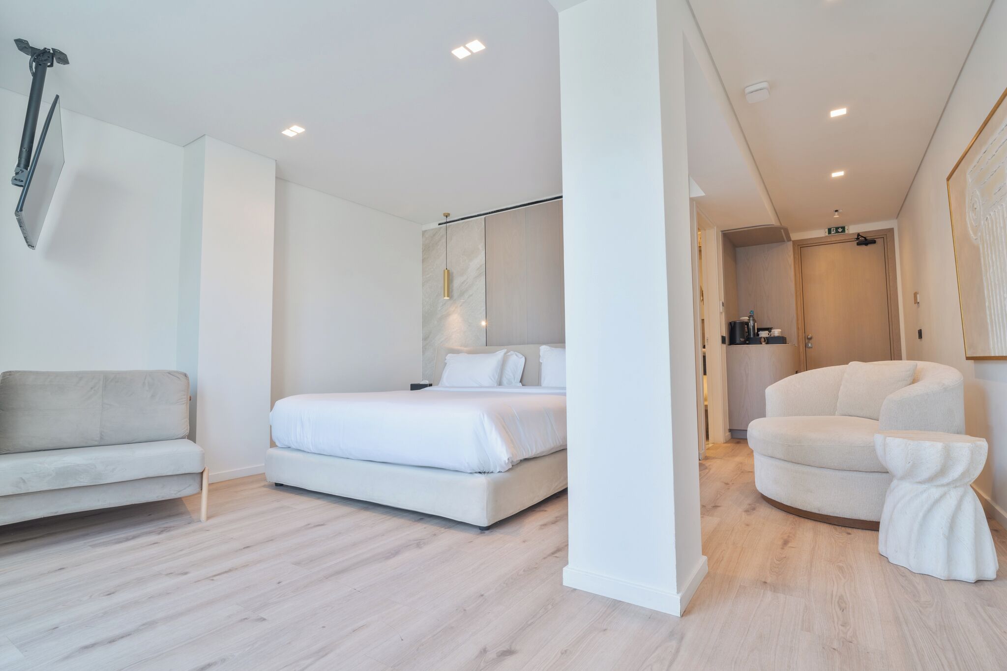 A modern hotel room with a bed, a sofa, a chair, and a small table.