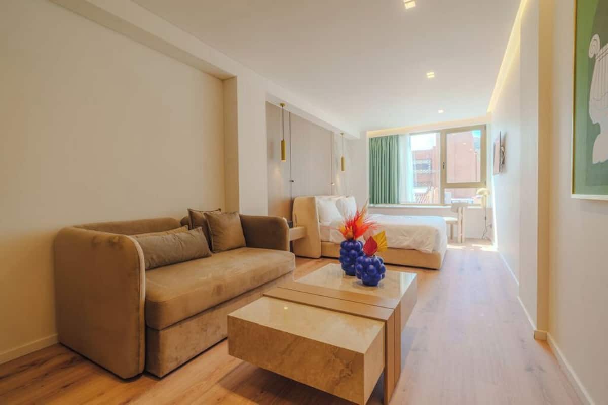 A modern living room with a sofa, coffee table, and a bed with a view.