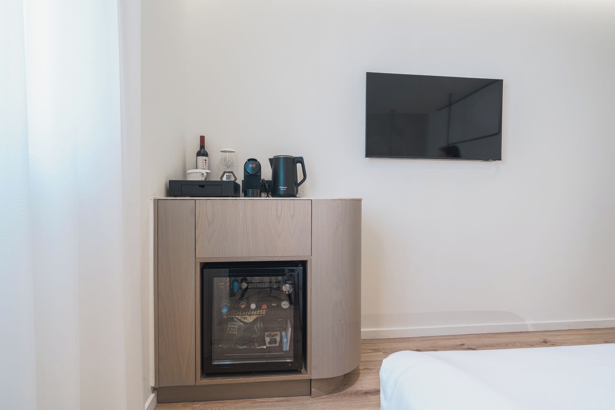 Quarto moderno com lareira embutida, televisão de tela plana presa na parede e um armário de madeira com vários objetos em cima.