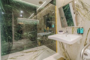 A modern bathroom with a glass-enclosed shower, a white sink, and marble walls.