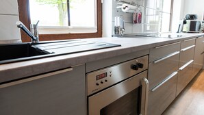 Una cocina moderna con un lavamanos de acero inoxidable, horno y un reloj digital que marca las 11:15.