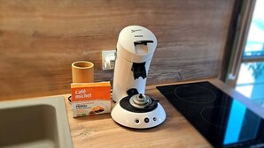 Una encimera de cocina con una máquina de café, una caja de cápsulas de café y un microondas.