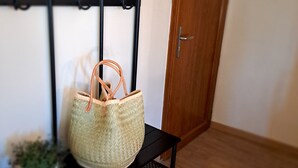 Una cesta de mimbre sobre un estante de metal negro en una habitación con una puerta de madera y una pared blanca.