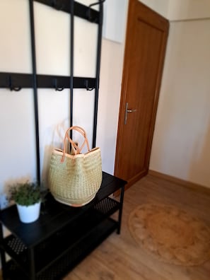 Un cesto di vimini su un ripiano in metallo nero, in una stanza con una porta in legno e una parete bianca.