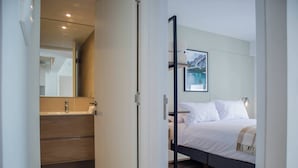 Ein modernes Schlafzimmer mit Bett, Nachttisch und einem großen Fenster.