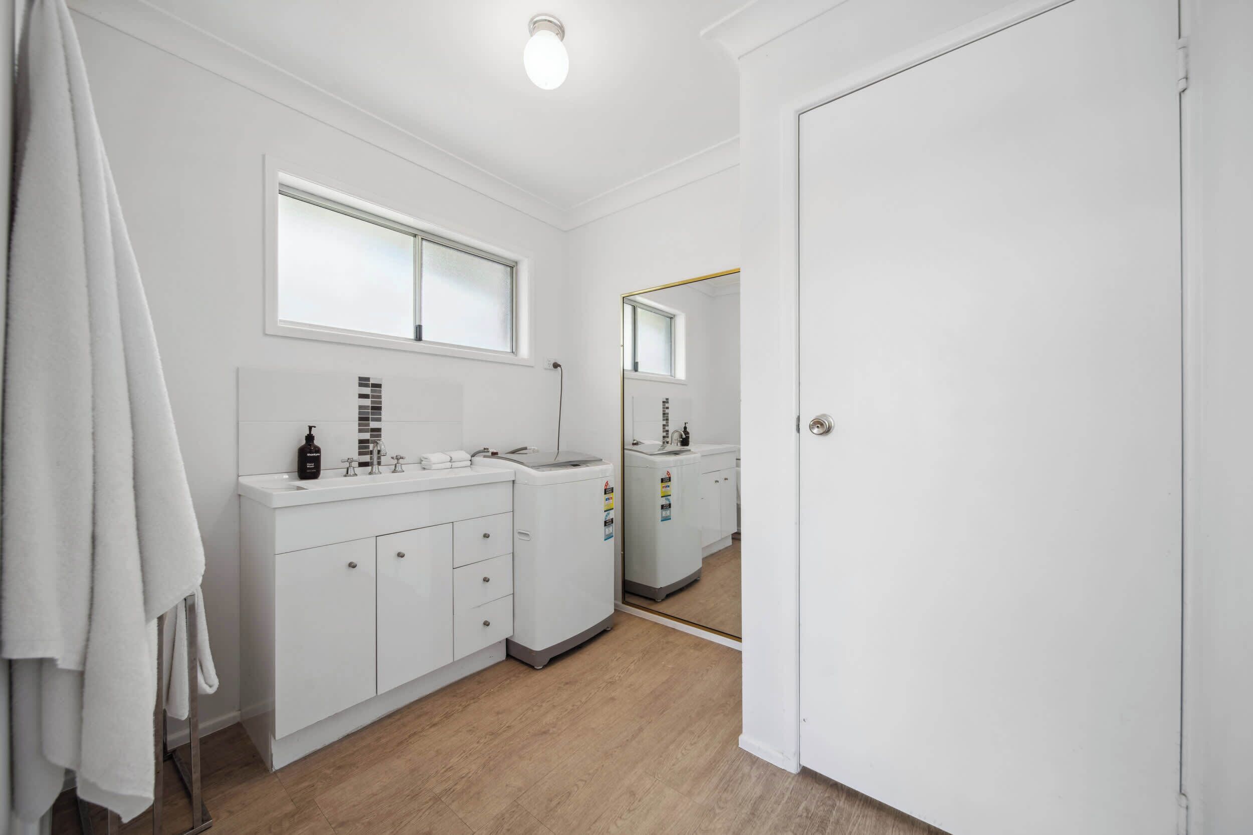 A bathroom with a white sink, mirror, and towel rack.