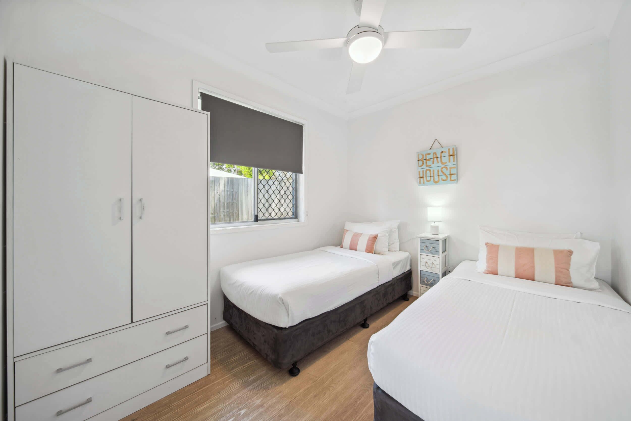 A bedroom with a bed, a wardrobe, a bedside table, a lamp, and a window with a view.