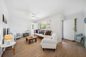 A living room with a sofa, a coffee table, a lamp, and a ceiling fan.