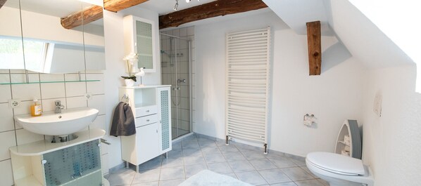 Un baño moderno con lavamanos, espejo y retrete blancos.