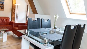 Een moderne woonkamer met een rode bank, een glazen salontafel en zwarte stoelen.