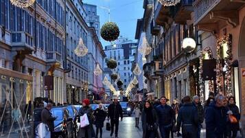A street lined with buildings, decorated with hanging spherical ornaments and lights.