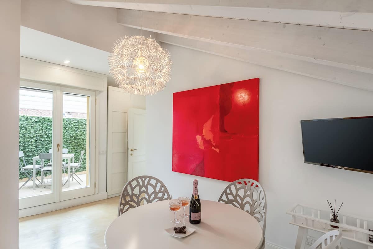 A dining area with a round table, two chairs, a bottle of champagne, and two glasses.