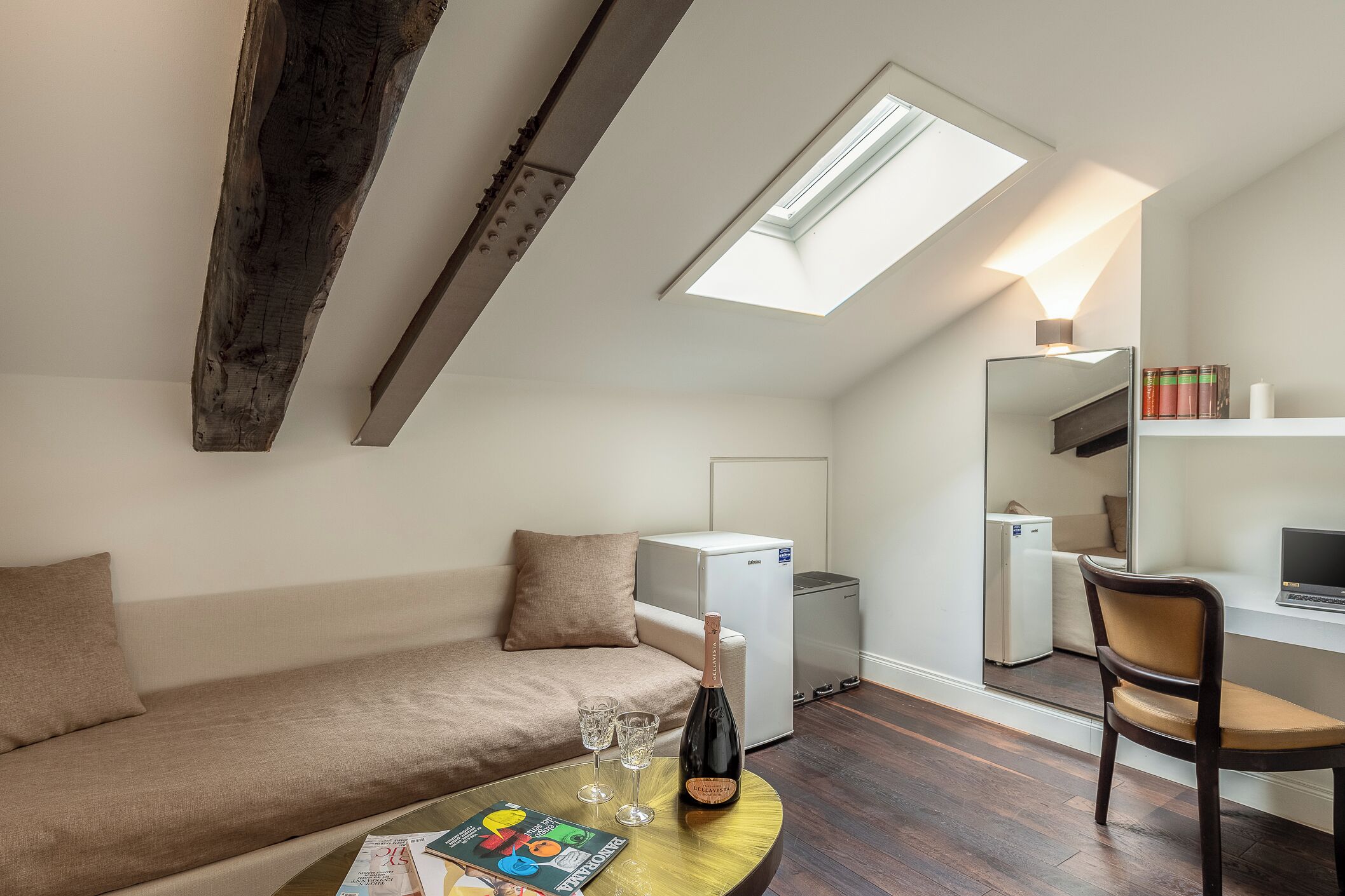 Un appartement moderne de style « loft », comprenant un lit en mezzanine, une kitchenette, un coin repas et un espace de vie avec un canapé et une table basse.