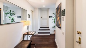 Un pasillo con un banco, una lámpara, un espejo y una puerta que da a la habitación 503.