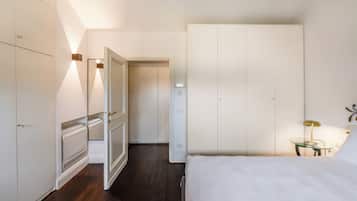 A bedroom with a bed, a wardrobe, a radiator, and a nightstand with a lamp.