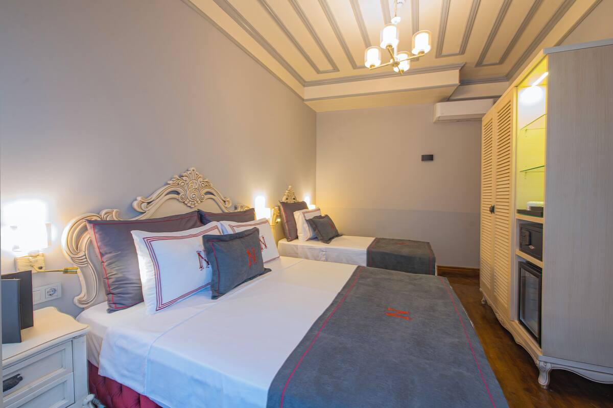 A hotel room with two beds, a wardrobe, and a chandelier.