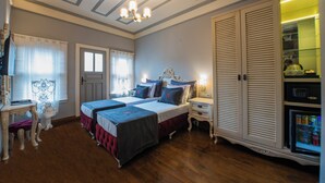 A bedroom with two beds, a wardrobe, a bedside table, a chair, and a ceiling light. - NİA SULTANAHMET HOTEL (Istanbul)
