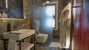 A bathroom with a large sink, toilet, and shower area. There is a robe hanging on the wall and a towel on the floor. - NİA SULTANAHMET HOTEL (Istanbul)