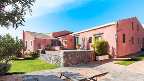 A red building with a stone wall and a paved patio area with chairs.