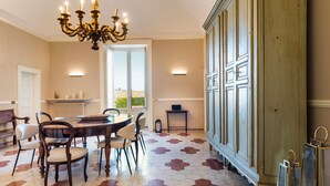 A dining area with a round table, chairs, a chandelier, and a patterned floor.