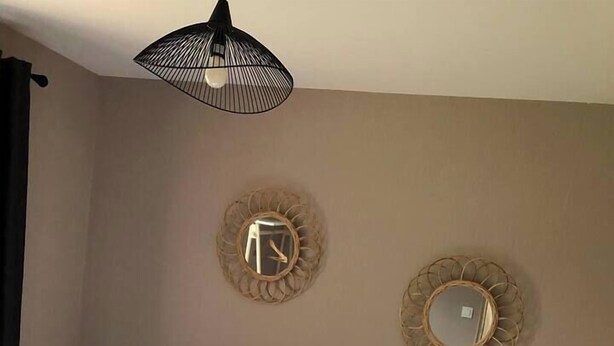 Un dormitorio con una cama, dos espejos en la pared y una lámpara colgante.