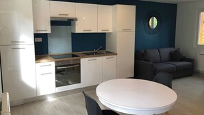 Una cocina moderna con armarios blancos, una mesa de comedor redonda y una pared de acento azul oscuro.