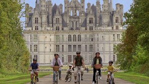 A group of cyclists on a paved path with a large, historic building in the background. - 1. Les gîtes de Joséphine Gîte a Chateau de la loire (Courbouzon)