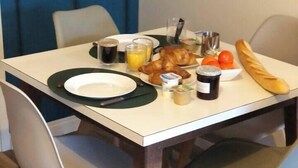 A dining table with plates, croissants, juice, and a baguette. - 1. Les gîtes de Joséphine Gîte a Chateau de la loire (Courbouzon)